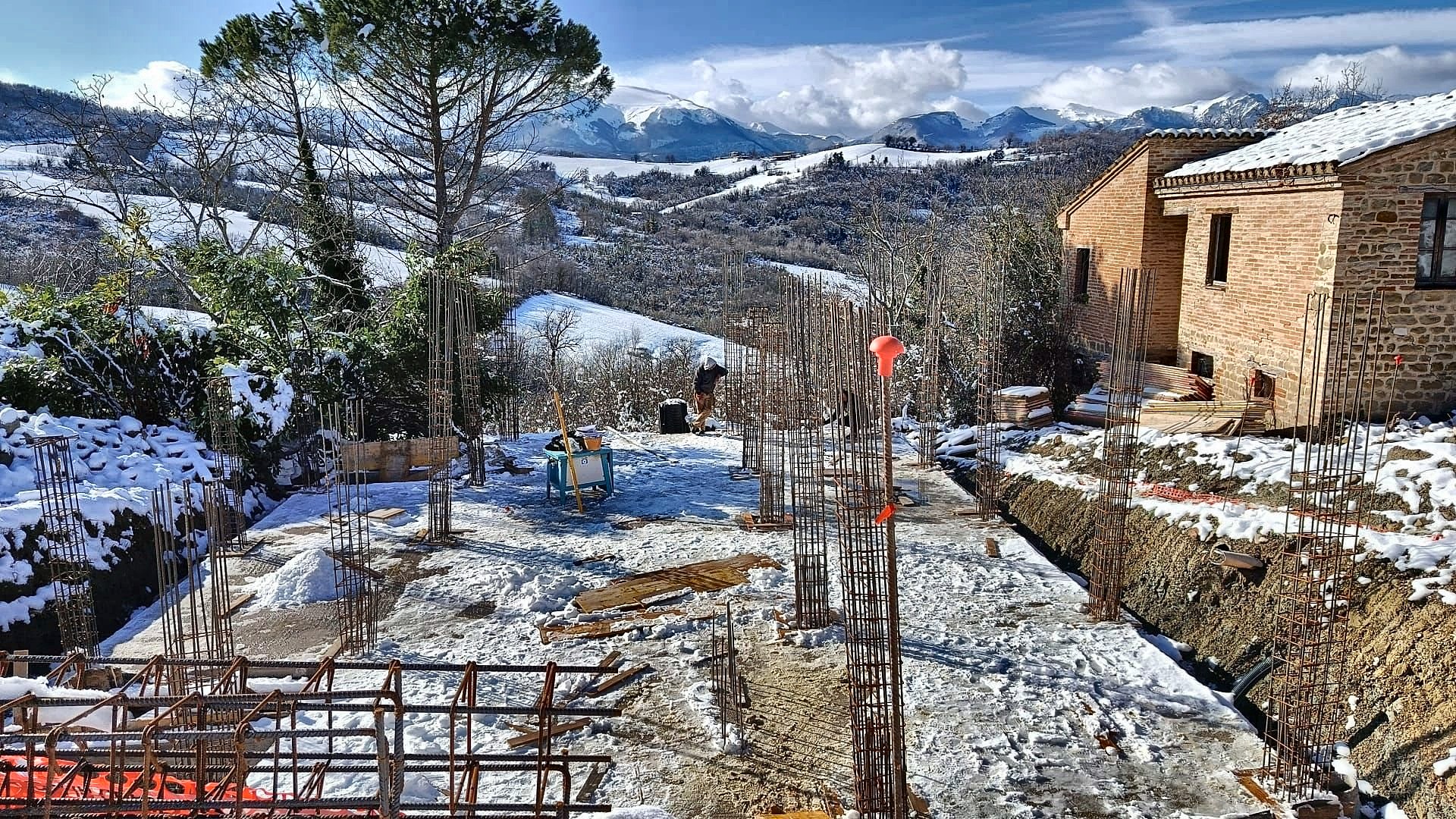 Fondazioni completate e armature dei pilastri sotto la neve, con i Monti Sibillini sullo sfondo