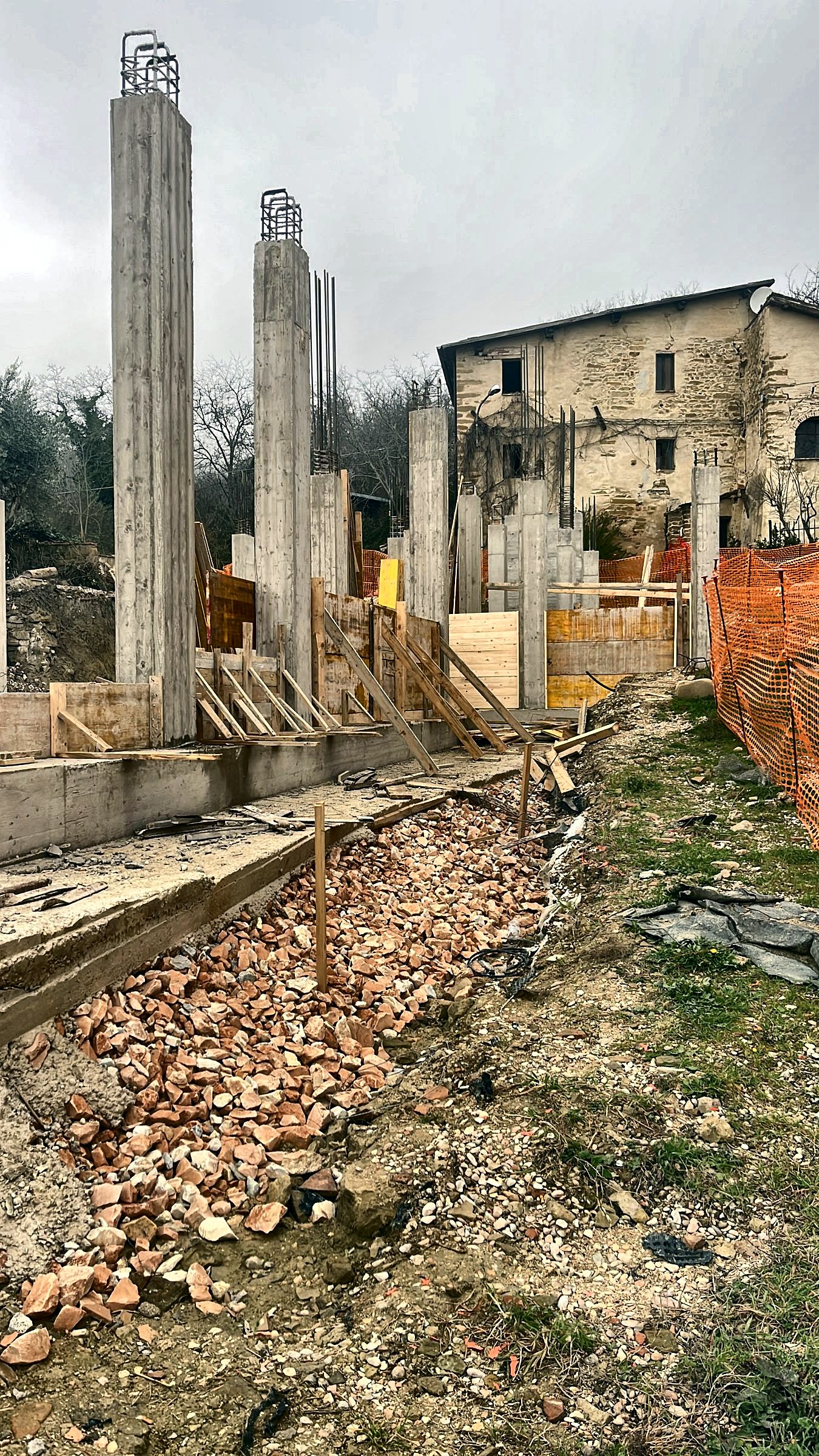 Pilastri in cemento armato in elevazione con le armature di ripresa, vespaio in laterizio in primo piano